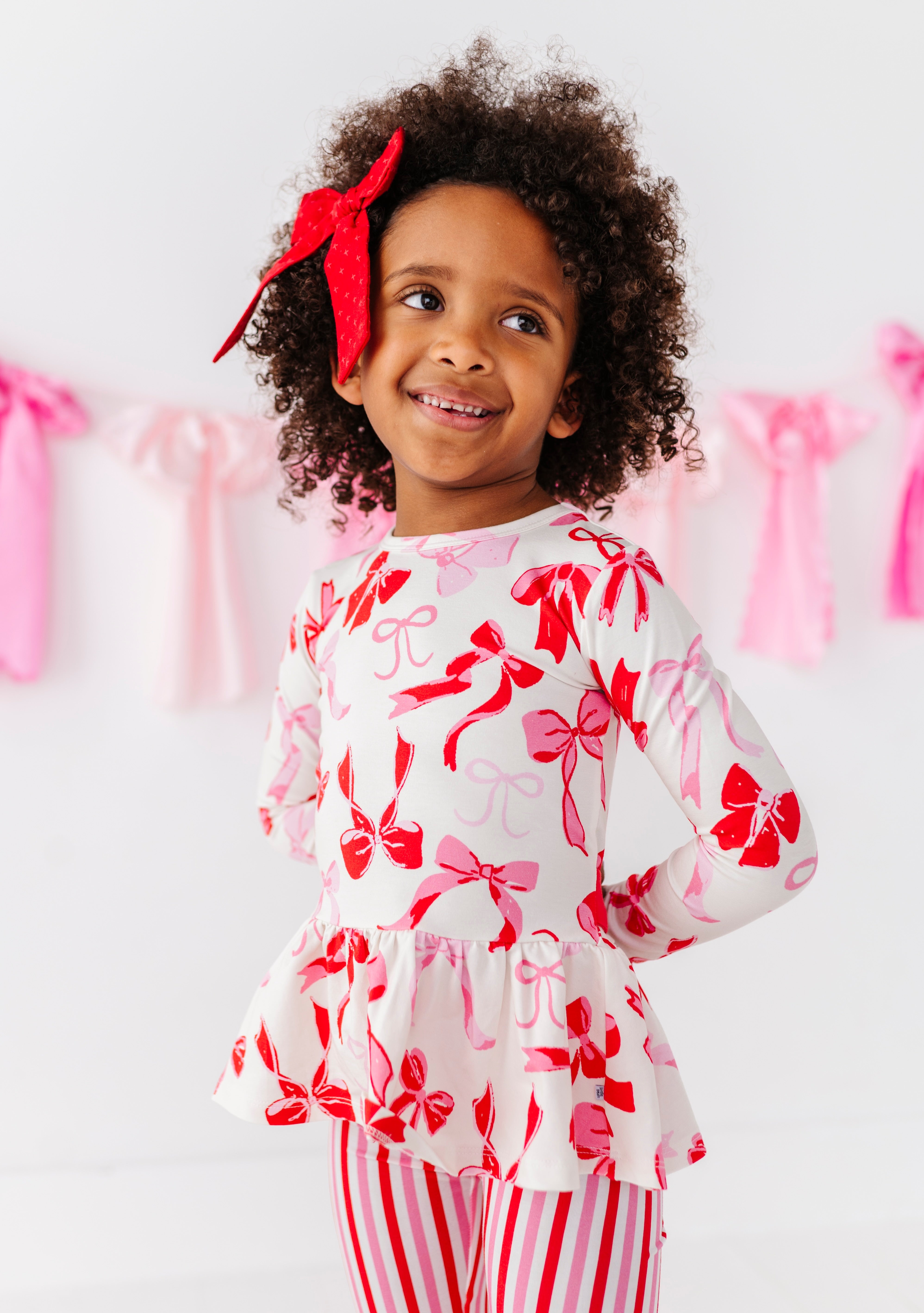 Toddler wearing Blushing Bows bamboo cotton peplum top with pink and red bow print